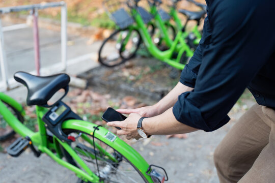Businessman using mobile app scanning QR code for rental bicycle on the work, eco transport concept