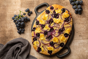 Focaccia with red onion, brie cheese and strawberry grape, homemade flat leavened oven-baked Italian bread. Top view.