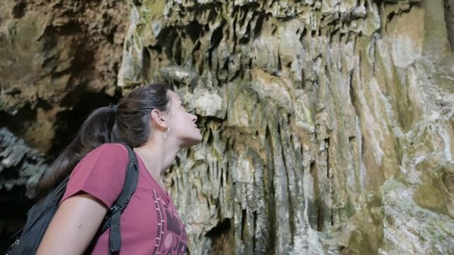 Close-up of a brunette and attractive girl observing the rugged limestone walls with delicate stalactites and stalagmites in the Murci&eacute;lago Cave in Sierra Calderona, in Altura, Castell&oacute;n