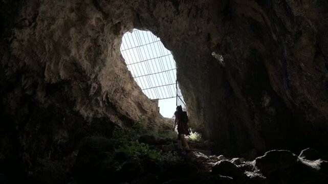 Girl hiker going out through the narrow opening of the Cueva del Murci&eacute;lago in the Sierra Calderona, in Altura, Castell&oacute;n