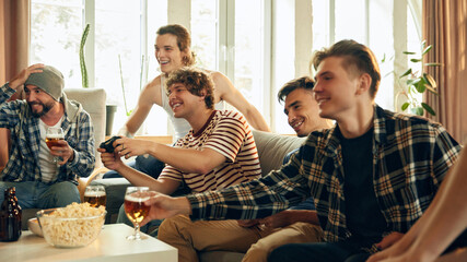 Intense focus and competitive energy fill room as friends engage in fierce match. Snacks, beers, and laughter keep atmosphere lively and fun. Concept of football fans, sport evens, cybersport.