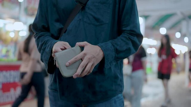 A man's hand opens his wallet. His hand looks for money in a black wallet, lack of money due to economic downturn, anxiety, spending spree, stress and worry, unemployed and no money.