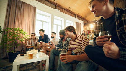 Moment of excitement as everyone leans in, engaged in game. Friends, snacks, and good vibes fill room as they celebrate small victories. Concept of football fans, sport evens, video games, cybersport.