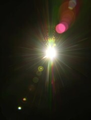 Obraz premium Lens flare Overlays. A dynamic and vibrant display of light, featuring a bright white sun at its center, surrounded by a myriad of colorful light rays and bokeh effects in the background.
