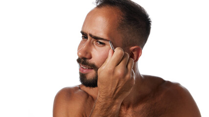 Obraz premium Portrait of handsome young bearded man taking care after his appearance, using tweezers, plucking eyebrows isolated on white background. Concept of male beauty, skin care, hygiene, health, cosmetics