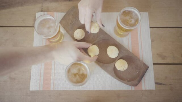People baking chipa bread together on a wooden table, enjoying beer and homemade snacks, capturing the joy of togetherness over food