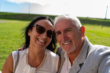 Fototapeta premium beautiful happy and smiling middle-aged couple dressed elegantly taking a selfie during a ceremony in the countryside