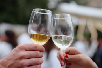 Toasting with white wine at an outdoor event.