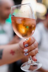 Hand holding a glass of rose wine with a blurred background.