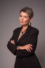 A businesswoman poses in a photo studio in a silver jumpsuit and a black stiletto dress.