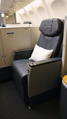 Fototapeta premium A black leather seat in an airplane with a white pillow.