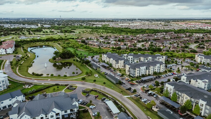 Mixed-use development area with pond water fountain, apartment complex, residential neighborhood, industrial zoning warehouses in fast growing area Pflugerville northeast of downtown Austin, TX