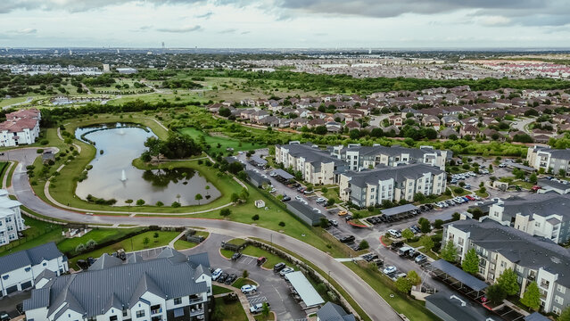 Mixed-use development area with pond water fountain, apartment complex, residential neighborhood, industrial zoning warehouses in fast growing area Pflugerville northeast of downtown Austin, TX