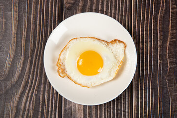 fried egg in a white plate on table.