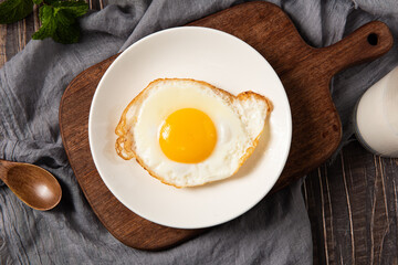 fried egg in a white plate on table.