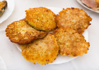 Fried grated potato pancakes with sour cream on white plate
