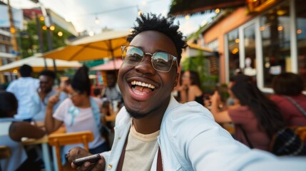 Fototapeta premium A young man in glasses takes a selfie at a cozy café, his relaxed, happy demeanor blending seamlessly with the laid-back, charming setting.