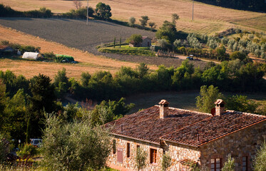 A tranquil countryside setting featuring a rustic stone house surrounded by lush green fields and landscapes, illuminated by the warm glow of the setting sun in Provence France
