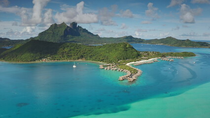 Topical island in French Polynesia with luxurious overwater bungalows resort and yacht sailing in...