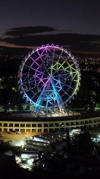 Portrait drone shot toward the illuminated ferris wheel at Aztlan Park, CMDX