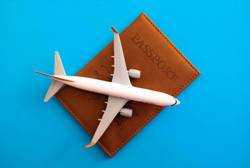 Travel and flight concept, miniature airplane on a brown passport on a blue background