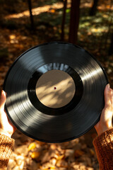 woman hands holding a vinyl record on autumn background