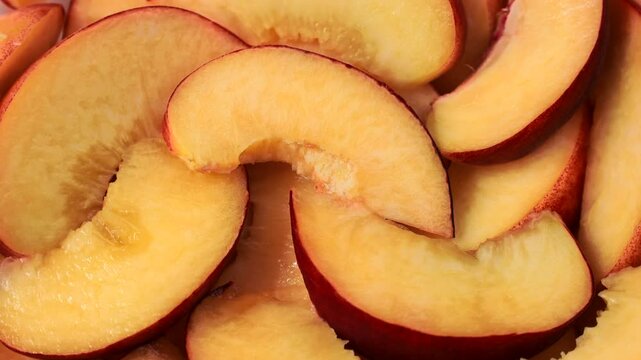 Bright orange and red peach slices circle rotation close up top view