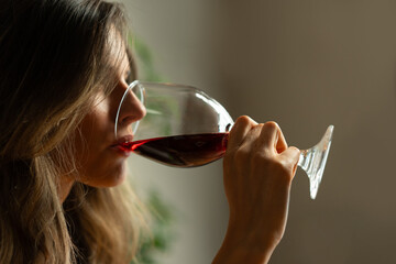 Young woman tasting red wine: sommelier, wine appreciation, ombre hair, profile view, soft lighting, sensory experience