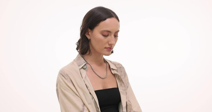 Upset woman with wrists tightly locked in handcuffs on white background. Frustrated female tries to make sense of unexpected situation slow motion - Powered by Adobe