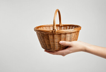 Hand holding a wicker basket on a white background
