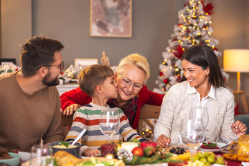 Little boy kissing his grandmother while having family Christmas dinner