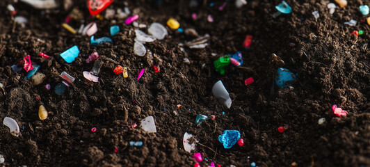 Soil with colorful plastic pieces scattered across it, symbolizing the impact of microplastic pollution on nature