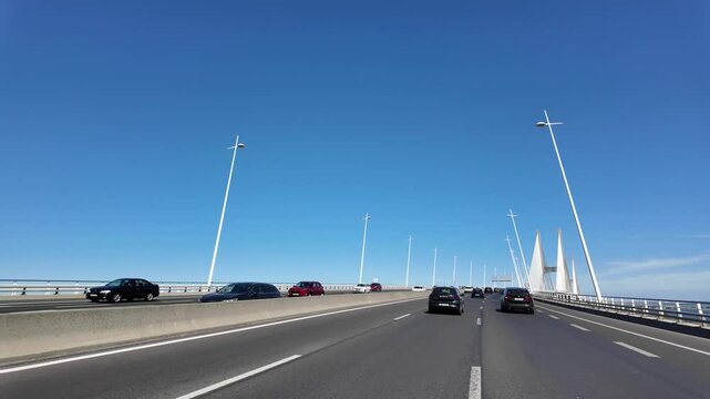 Crossing the Vasco da Gama Bridge in Lisbon, Portugal, from a car, with views of the Tagus River and the surrounding landscape.
