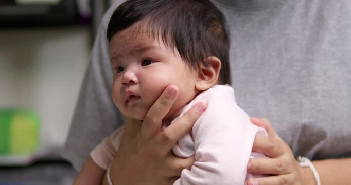 Tapping the back of a newborn infant, the mother is helping her child to burp to release some gas after having its meal.