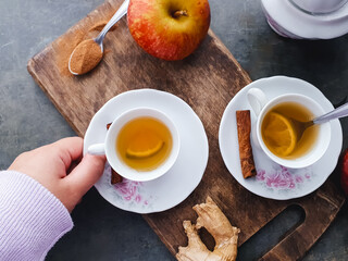Hand picking up cup of apple and citrus tea and rustic background