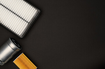Top view of stack of car parts, filters on black background. Car oil filter, air filter and fuel...