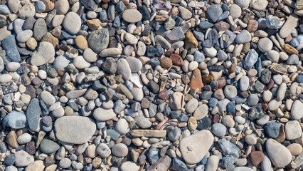 The beach showcases a diverse collection of smooth and colorful pebbles scattered along the shore, reflecting the tranquility of the day
