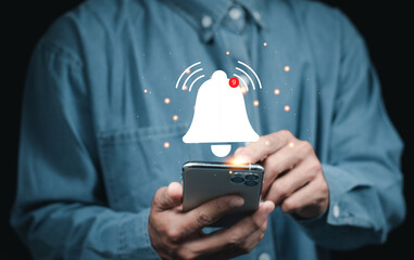 Businessman holding smartphone with virtual yellow bell ringing for application notification alert...