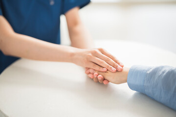 カウンセリングをしている医師が両手で患者の手を包み込んている。