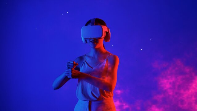 Woman player using VR transfer to fantastic metaverse fencing game box material neon by sword laser fantasy gaming space with lighting bokeh on blue smoke in meta 3D cyberspace world. Hallucination. - Powered by Adobe
