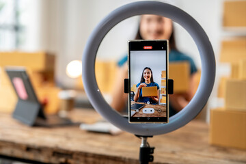 Young asian influencer unboxing package while recording video blog