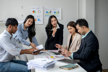 A group of people are sitting around a table with papers and a laptop