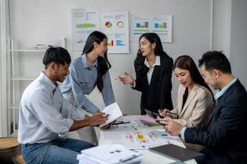 A group of people are sitting around a table with papers and a laptop