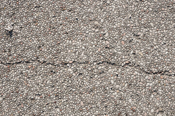 This photo shows a cracked concrete surface covered with small white pebbles, providing a textured background for your design projects.