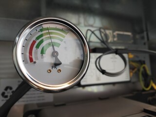 The image shows a close-up of a pressure gauge marked with PSI and temperature readings. The dial has green, yellow, and red zones, indicating varying pressure levels.