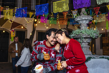 Mexican young couple or friends having fun in posada celebration for Christmas in Mexico Latin America, hispanic people