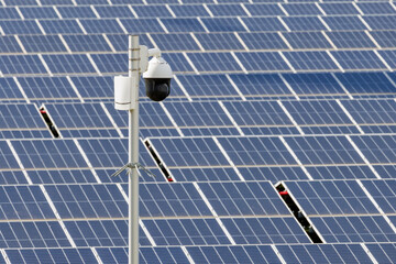 Surveillance camera in front of a large industrial field of solar panels