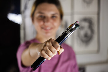 Artistic girl holding many dirty colorful used brushes.