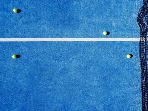 four balls on a blue paddle tennis court, aerial top view from a drone