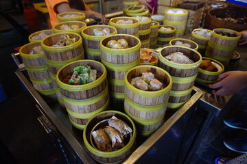 Traditional Chinese dim sum in metal bowl on wooden table. A lot of different kinds of food and drinks on the table